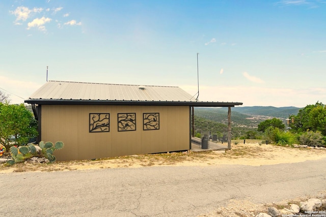 view of property exterior featuring an outbuilding, metal roof, and a mountain view