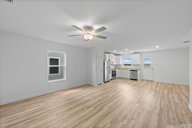 unfurnished living room with light hardwood / wood-style flooring, ceiling fan, and sink