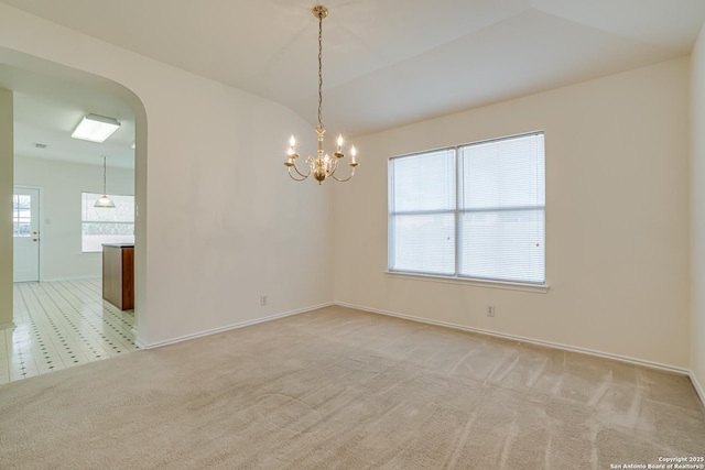 carpeted empty room featuring lofted ceiling and a notable chandelier