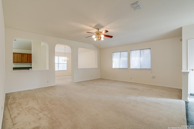 carpeted spare room featuring ceiling fan with notable chandelier