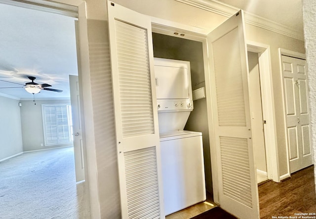 clothes washing area featuring dark carpet, crown molding, stacked washer and clothes dryer, and ceiling fan