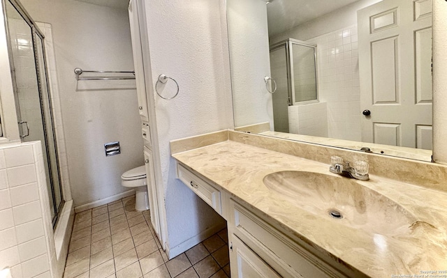 bathroom with an enclosed shower, vanity, toilet, and tile patterned floors