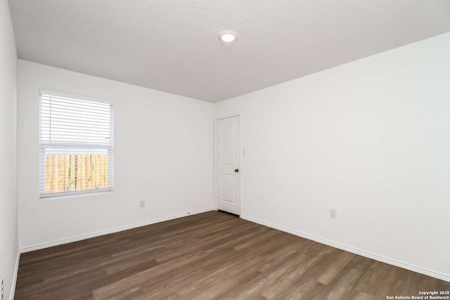 unfurnished room featuring dark hardwood / wood-style flooring and a textured ceiling