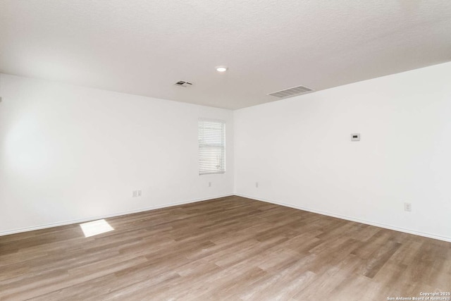 empty room featuring light wood-type flooring and a textured ceiling