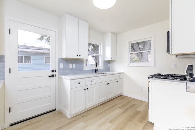 kitchen featuring white cabinetry, sink, tasteful backsplash, and light hardwood / wood-style floors