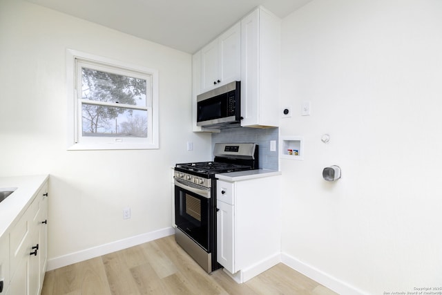 kitchen featuring white cabinetry, appliances with stainless steel finishes, tasteful backsplash, and light wood-type flooring