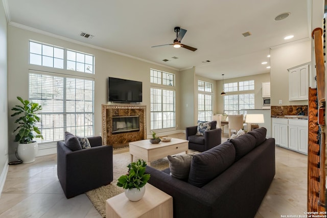 living room featuring a fireplace, ornamental molding, sink, and a wealth of natural light