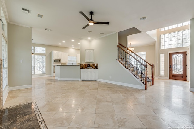 unfurnished living room with ceiling fan and crown molding