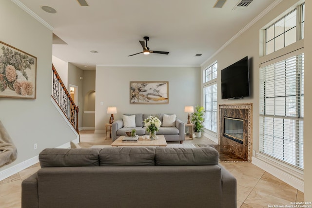 living room featuring ceiling fan, crown molding, and a fireplace