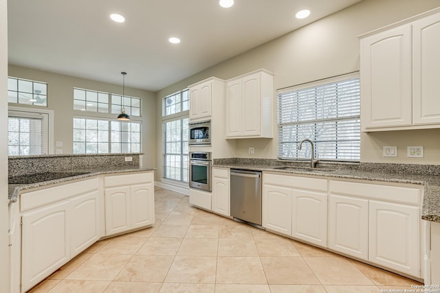 kitchen featuring sink, stone counters, white cabinetry, stainless steel appliances, and hanging light fixtures