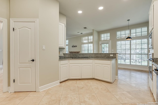 kitchen with white cabinetry, kitchen peninsula, dark stone counters, and decorative light fixtures