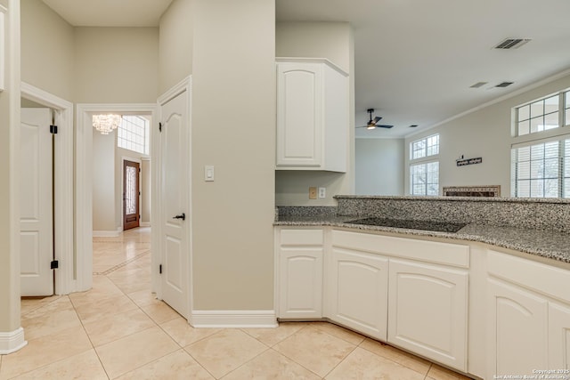 kitchen with white cabinetry, light tile patterned flooring, black electric cooktop, and stone countertops