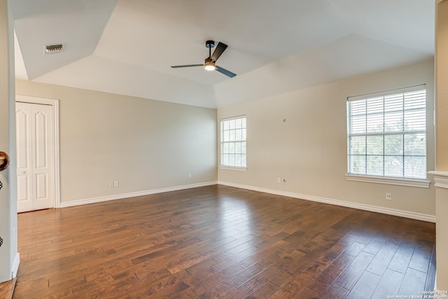 unfurnished room featuring a raised ceiling, ceiling fan, and dark hardwood / wood-style floors