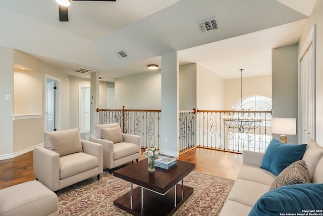 living room with ceiling fan with notable chandelier, lofted ceiling, and wood-type flooring