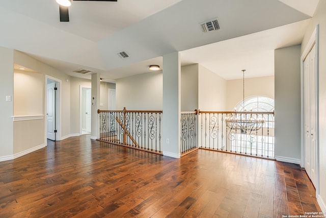 unfurnished room featuring ceiling fan with notable chandelier, dark wood-type flooring, and lofted ceiling