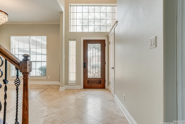 entryway with ornamental molding and light tile patterned floors