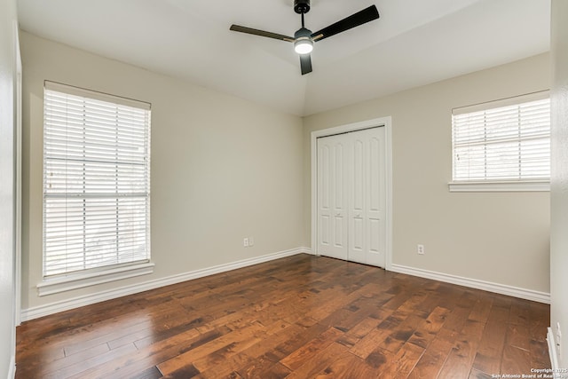 unfurnished bedroom featuring ceiling fan, a closet, dark wood-type flooring, and vaulted ceiling