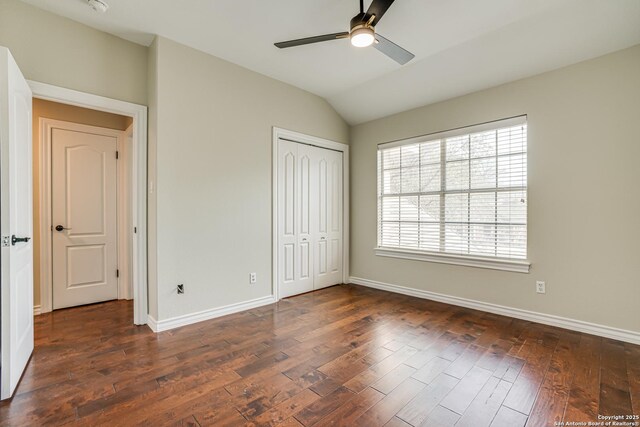 unfurnished bedroom with ceiling fan, dark wood-type flooring, vaulted ceiling, and a closet