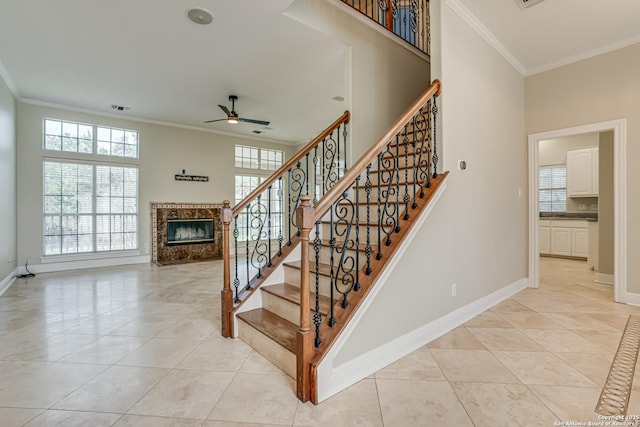 stairway featuring ornamental molding, a high end fireplace, tile patterned flooring, and ceiling fan