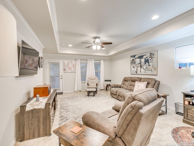 living room with baseboards, ceiling fan, a tray ceiling, and crown molding