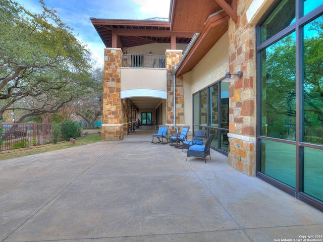 view of patio with a balcony and fence