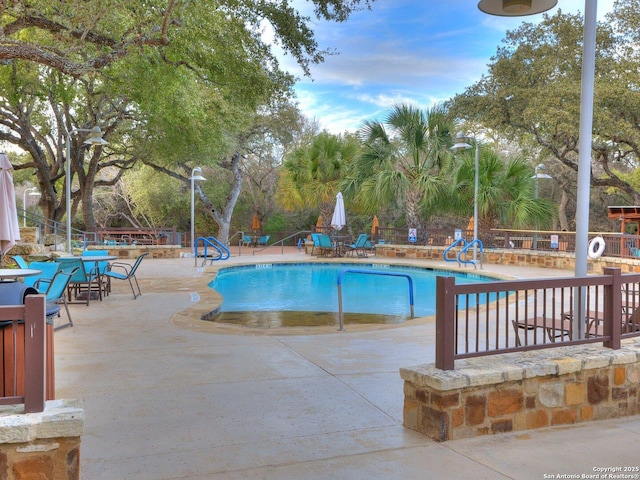 community pool with fence and a patio