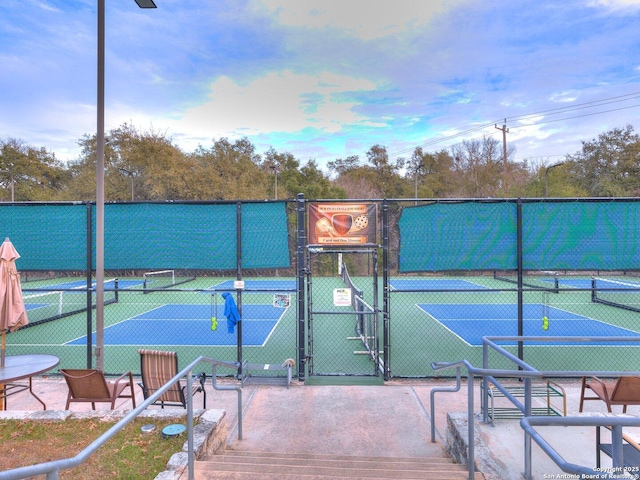 view of tennis court featuring fence and a gate