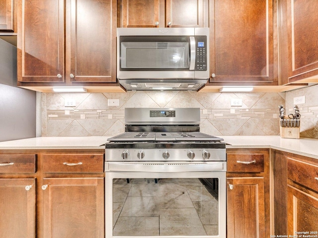 kitchen with brown cabinetry, appliances with stainless steel finishes, light countertops, and backsplash