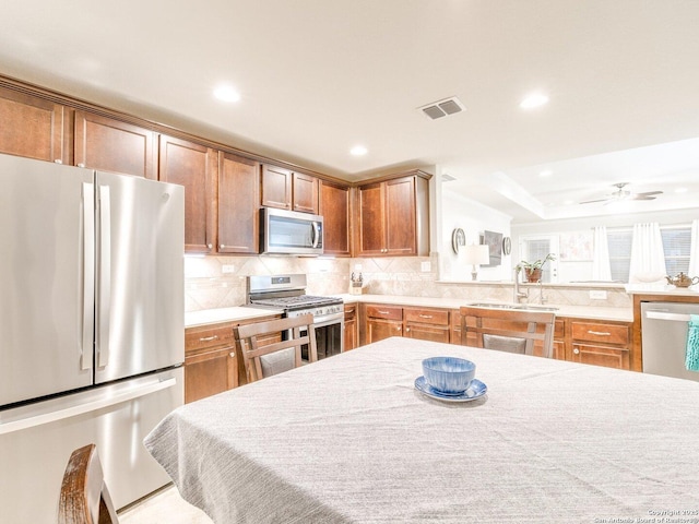 kitchen with tasteful backsplash, appliances with stainless steel finishes, light countertops, and a sink