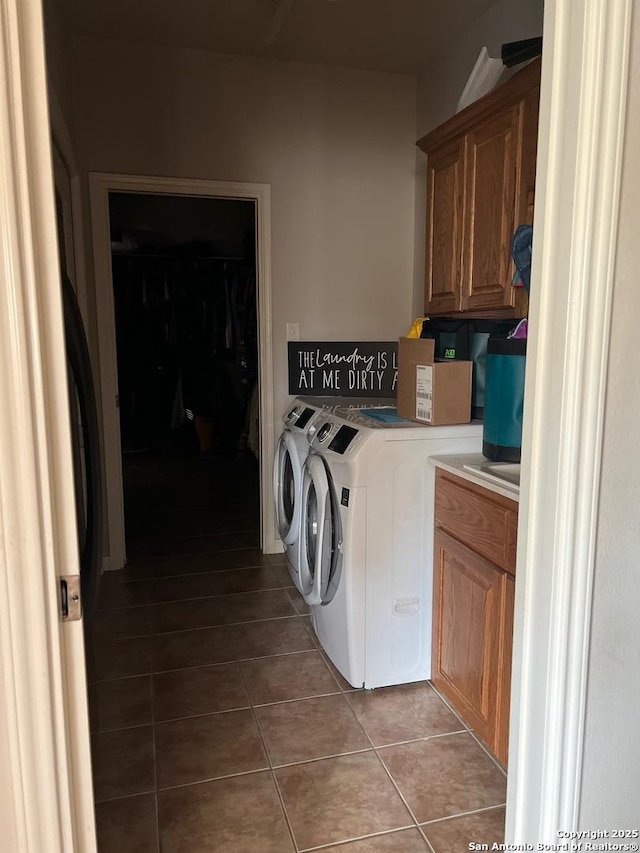 clothes washing area with light tile patterned flooring, washer and dryer, and cabinets