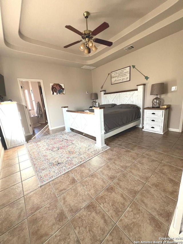 unfurnished bedroom with a tray ceiling, ceiling fan, and dark tile patterned floors