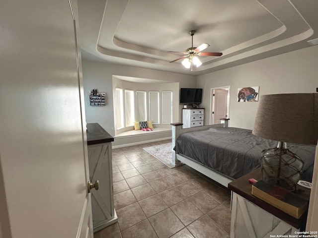 tiled bedroom with a raised ceiling and ceiling fan