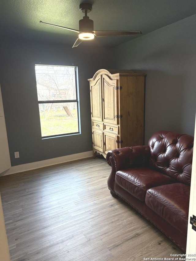 living room with a textured ceiling, ceiling fan, and light hardwood / wood-style flooring