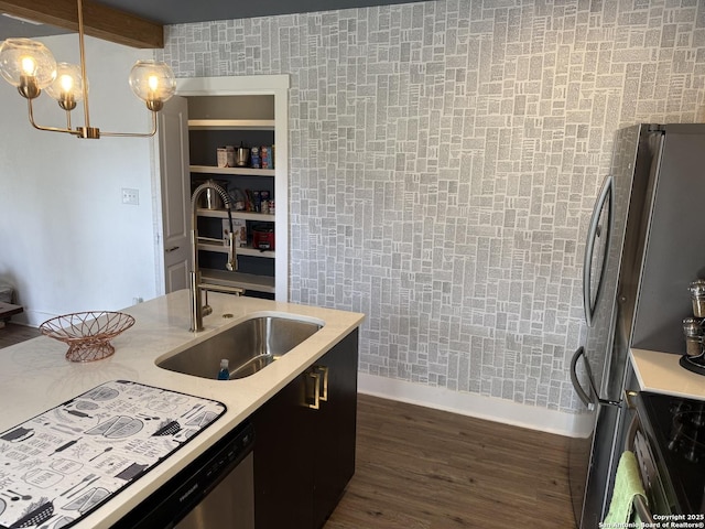 kitchen with appliances with stainless steel finishes, sink, dark wood-type flooring, and decorative light fixtures