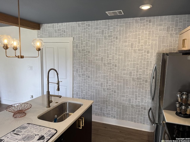 kitchen featuring sink, dark hardwood / wood-style floors, decorative light fixtures, stainless steel refrigerator, and beam ceiling