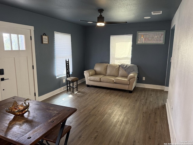 living room with ceiling fan, plenty of natural light, dark hardwood / wood-style flooring, and a textured ceiling