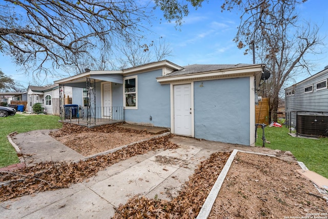 ranch-style home with cooling unit, covered porch, and a front lawn