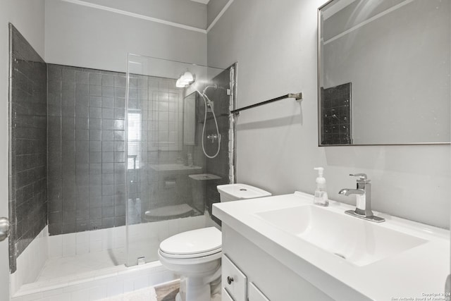 bathroom with toilet, vanity, and tiled shower