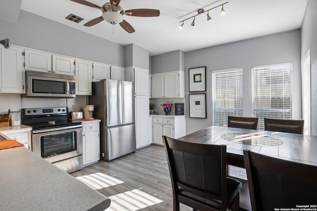 kitchen featuring light wood-type flooring, appliances with stainless steel finishes, white cabinets, and ceiling fan