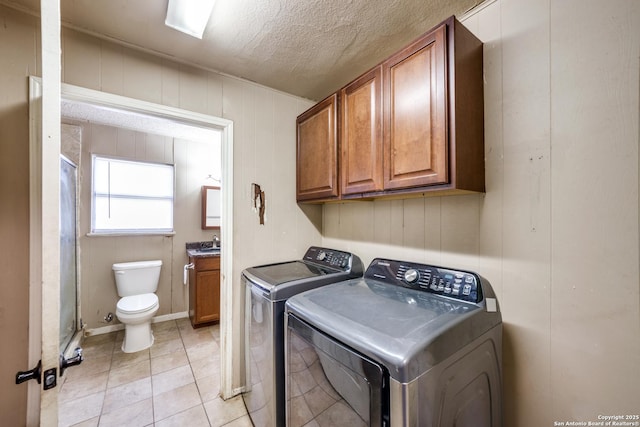 washroom featuring sink, a textured ceiling, light tile patterned flooring, and washer and clothes dryer