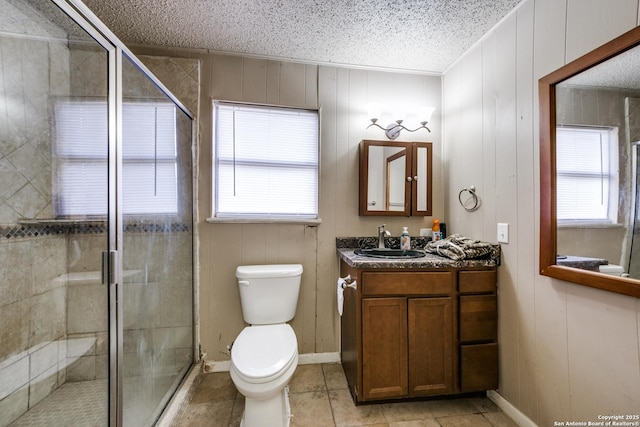 bathroom with a textured ceiling, toilet, vanity, and a shower with shower door