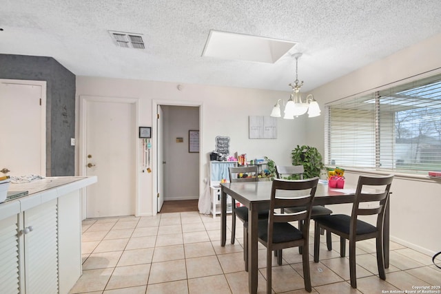 tiled dining area with an inviting chandelier and a textured ceiling