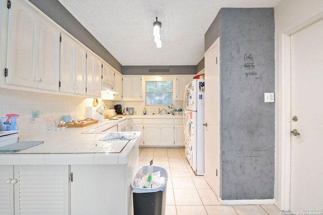 kitchen featuring white appliances, light tile patterned flooring, white cabinetry, kitchen peninsula, and tasteful backsplash