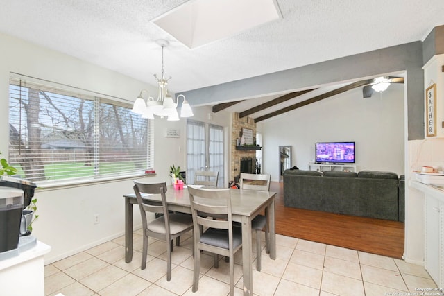 tiled dining space with a textured ceiling, vaulted ceiling with beams, a fireplace, and a notable chandelier