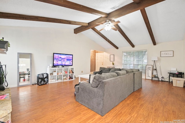 living room featuring hardwood / wood-style floors, ceiling fan, vaulted ceiling with beams, and a textured ceiling