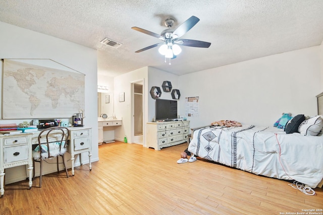 bedroom featuring ceiling fan, light wood-type flooring, and a textured ceiling