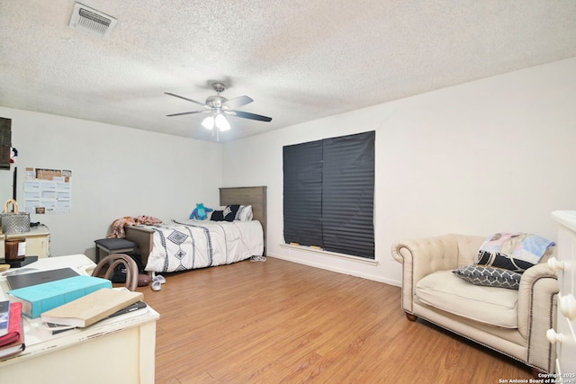 bedroom featuring ceiling fan, wood-type flooring, and a textured ceiling