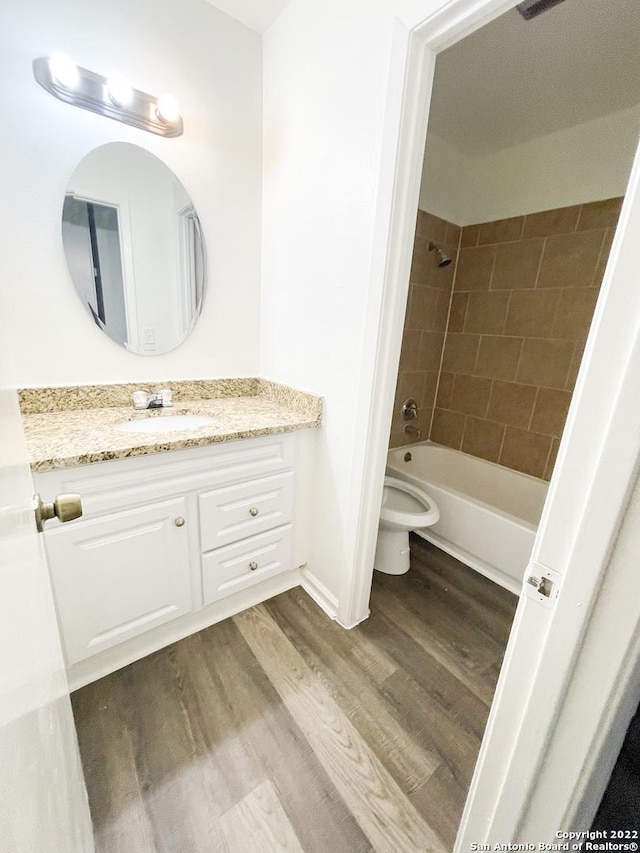 full bathroom with toilet, vanity, tiled shower / bath combo, and wood-type flooring