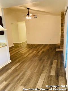 unfurnished living room featuring ceiling fan and dark wood-type flooring