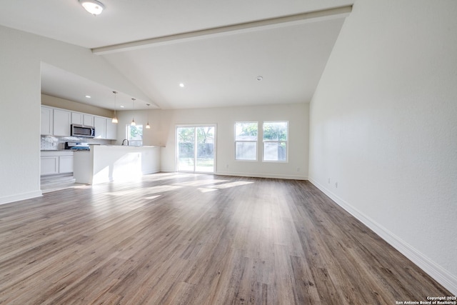 5023 Stockman Dr, San Antonio, TX 78247 - unfurnished living room featuring a sink, baseboards, vaulted ceiling with beams, and wood finished floors